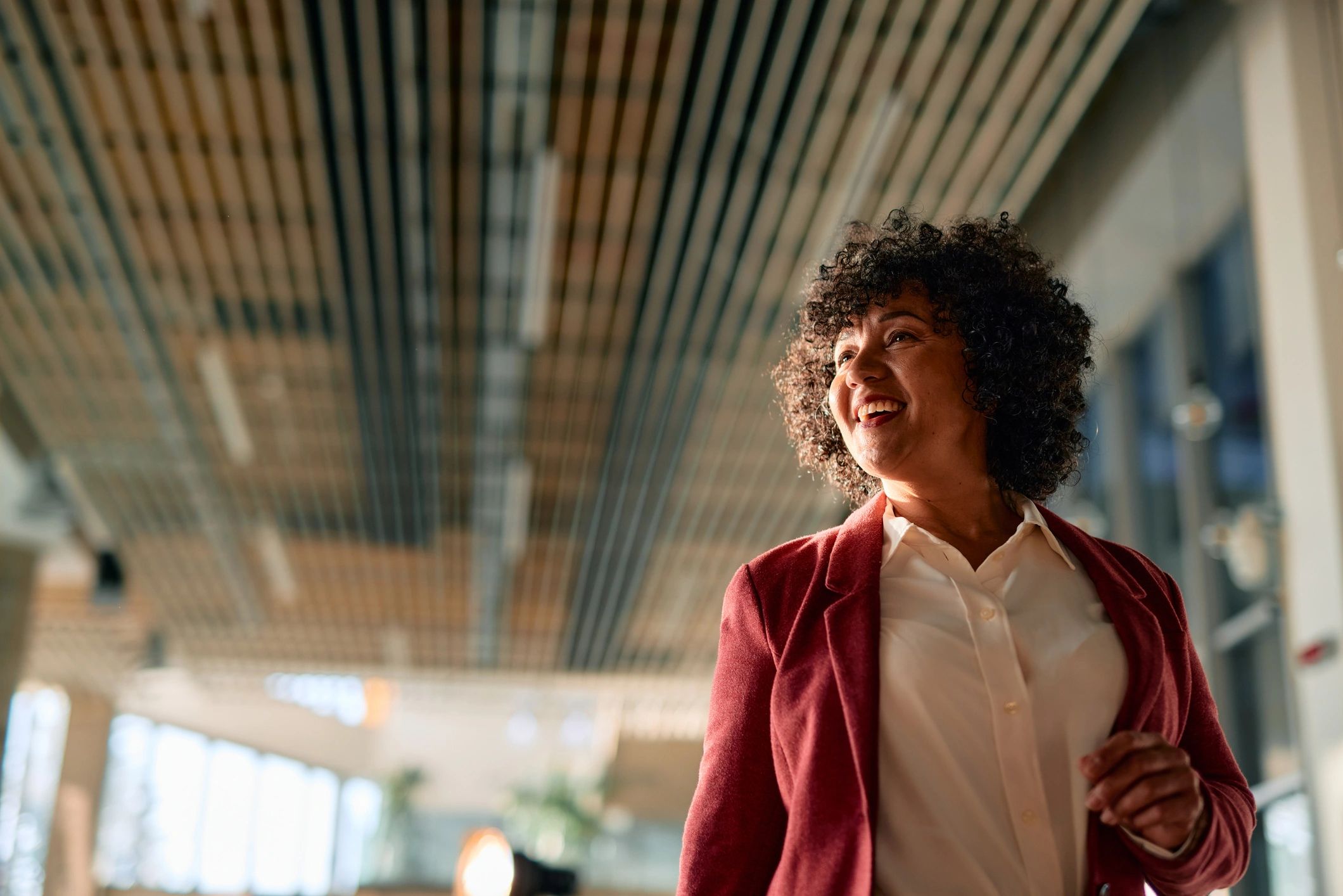 Smiling businesswoman walking in modern office building looking up